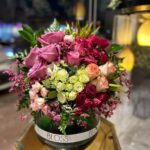 A vase containing a mix of baby roses and roses